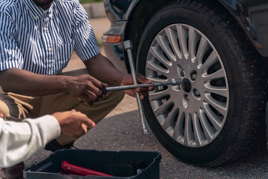 pexels-photo-9518257-9518257 An adult demonstrating how to change a tire to a teenager, focusing on teamwork and learning.